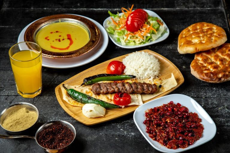 Platter of flame-grilled beef koobideh kababs served over saffron-topped basmati rice with grilled tomatoes, Shirazi salad, and appetizers at the best Persian restaurant in Los Angeles.