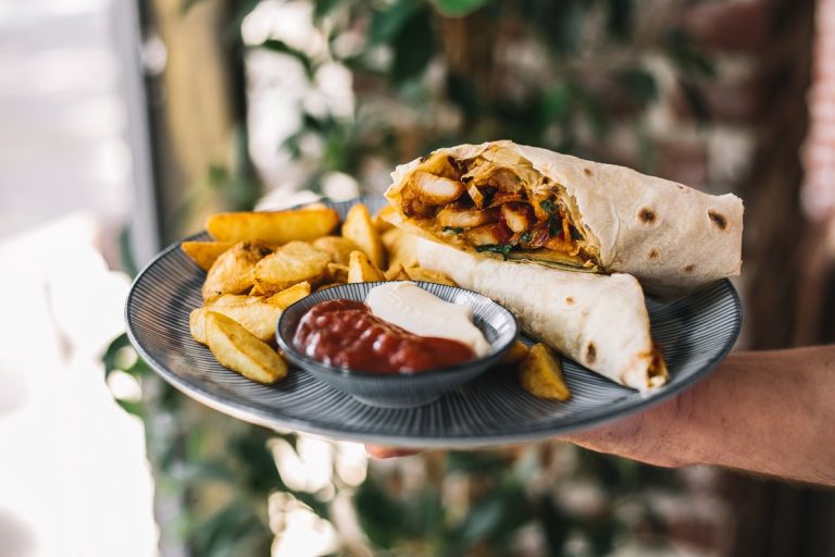 Freshly carved flame-grilled meat served in a warm pita with tzatziki, tomatoes, and onions for authentic gyros in Los Angeles.